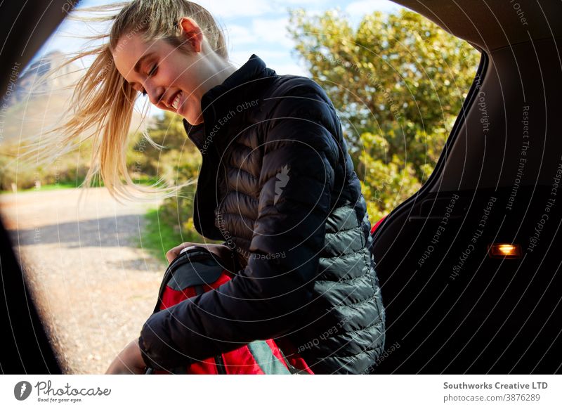Frau in offener Heckklappe des Autos legt Thermoskanne in Rucksack, bereit für Wanderung auf dem Land laufen wandern Junge Frauen Spaziergang aktiv Verpackung