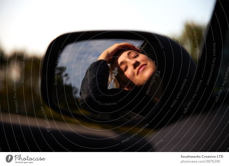 Reflexion im Fahrspiegel einer jungen Frau auf Autoreise Urlaub, die sich aus dem Fenster eines Mietwagens lehnt PKW Autovermietung Junge Frauen Feiertag fahren