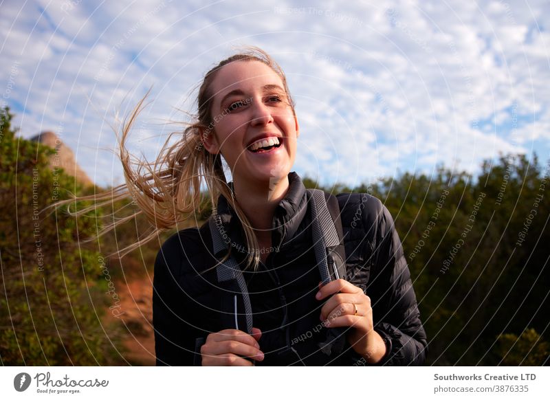 Porträt einer jungen Frau mit Rucksack beim Wandern auf einem Pfad durch die Landschaft Lächeln Junge Frauen Wanderung wandern Spaziergang laufen aktiv Feiertag