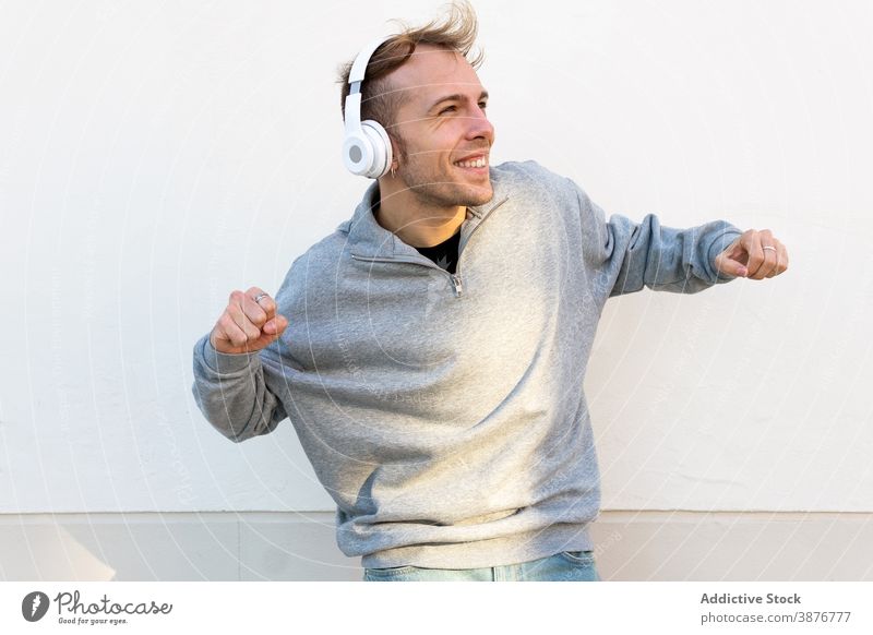 Optimistischer Mann mit Kopfhörer tanzt auf der Straße Tanzen heiter Musik Hipster Glück Energie urban jung männlich lässig Wand zuhören Lifestyle Klang Gesang