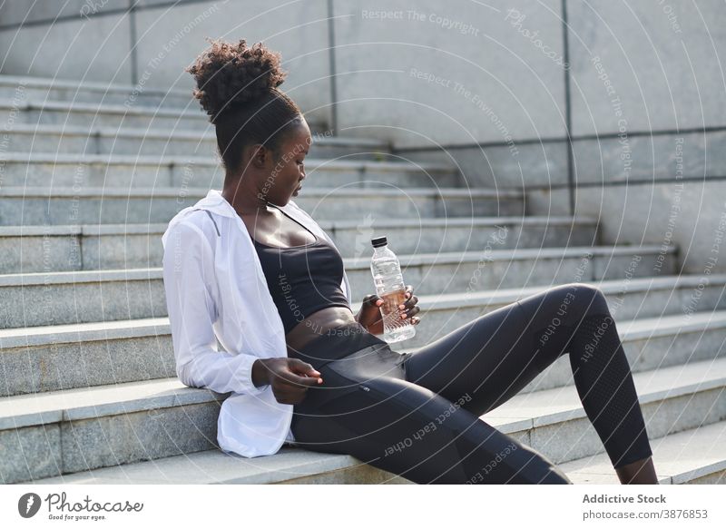 Ethnische Sportlerin trinkt Wasser in der Stadt trinken Training Läufer Frau Großstadt Erfrischung Durst sportlich ethnisch schwarz Afroamerikaner Wellness