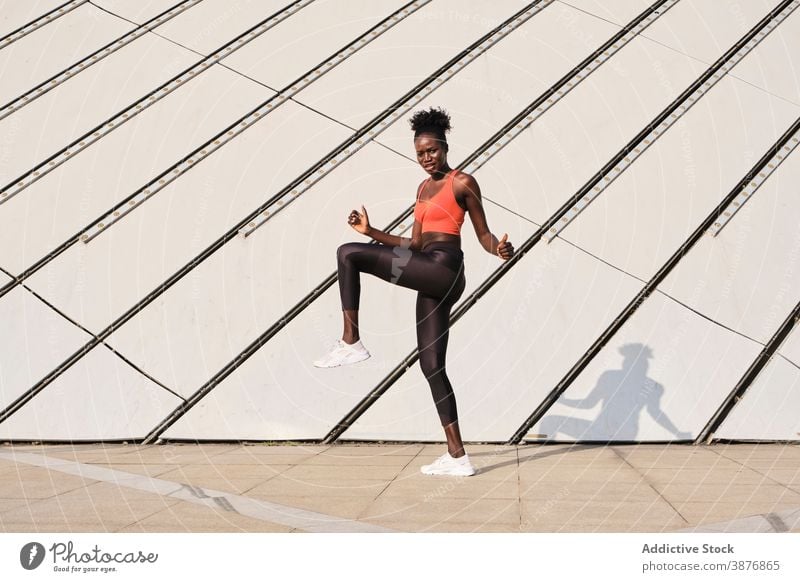 Athletische schwarze Frau macht Übungen auf der Straße Aufwärmen Sportlerin Training Bein Dehnung ethnisch Afroamerikaner dynamisch beweglich physisch Fitness
