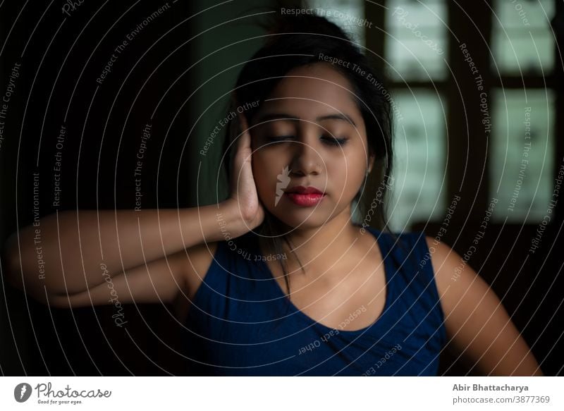 Eine junge und attraktive indisch-bengalische brünette Frau in aktiver Kleidung macht Yoga, nachdem sie morgens vor dem Fenster in ihrem Zimmer aufgewacht ist. Indischer Lebensstil.