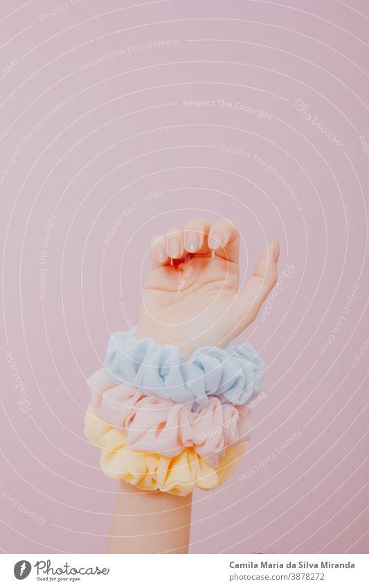 Hand mit bemalten Nägeln und Scrunchies auf dem Arm. Im Atelier gemachtes Foto mit rosa Hintergrund. Kunst Schönheit Nahaufnahme Mode Frau feminin festlich