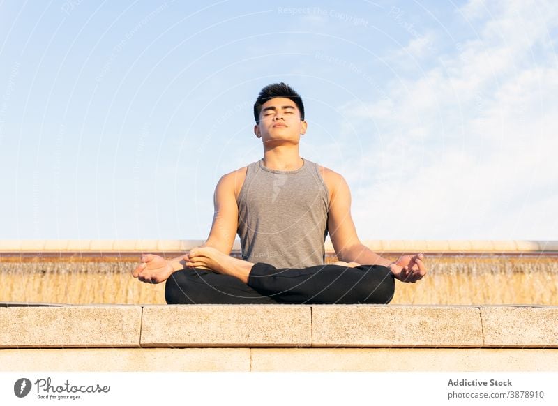 Fokussierter Mann übt Meditation auf Lotus-Pose Yoga Großstadt Stressabbau asiatisch Achtsamkeit mental ruhig ethnisch männlich Konzentration üben Energie