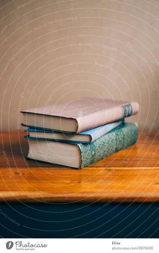 Drei Bücher liegen gestapelt auf einer Kommode aus Holz Bildung Literatur Buch Lesestoff alt Roman lesen Stapel Bücherstapel