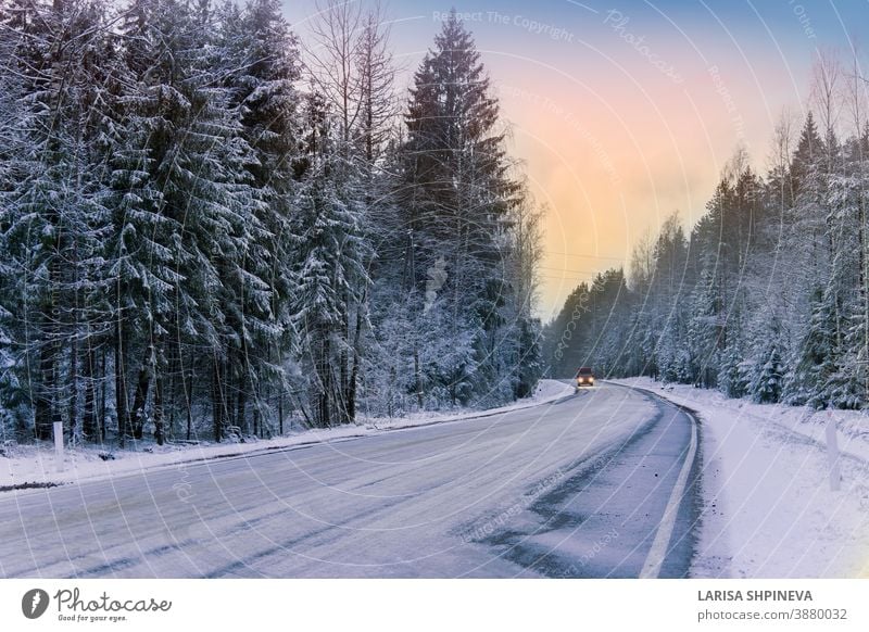 Auto fährt auf leerer, verschneiter Strasse im Winterwald. Wunderschöne frostig weisse Landschaft in der Morgendämmerung. Straße Saison Wald Eis Szene