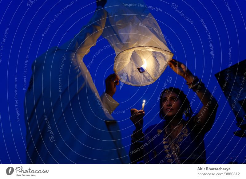 Ein indisch-bengalisches Ehepaar feiert Diwali, indem es in der blauen Stunde fliegende Laternen am Himmel anzündet. Indischer Lebensstil und Diwali-Feier