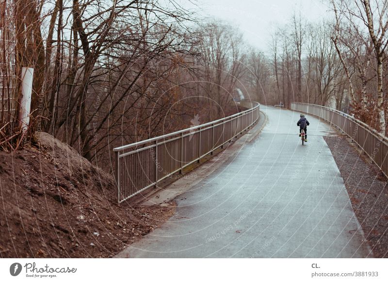 kind auf fahrrad Fahrrad Fahrradfahren Kind Wege & Pfade Winter trist Verkehrswege Mobilität Fahrradweg Bewegung