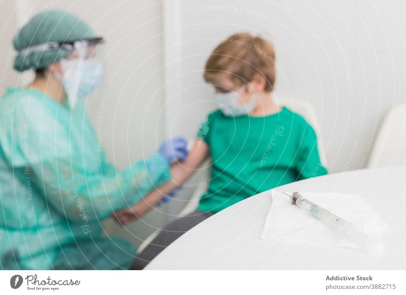 Arzt bereitet Kind auf Impfung gegen Coronavirus vor desinfizieren Einspritzung geduldig Impfstoff steril Bund 19 neue Normale Tracht Sanitäter Klinik behüten