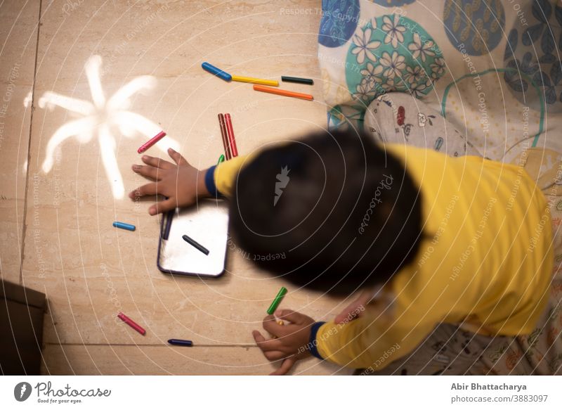 Ein indisch-bengalischer kleiner Junge, der an einem Ferienmorgen zu Hause mit Farbstiften/Skizze spielt. Indischer Lebensstil Asien asiatisch Baby schön