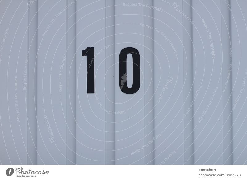 Zehn, volle Punktzahl. Die schwarze Zahl zehn auf einem Garagentor. Nummerierung, Zuordnung markierung garage garagentor geschlossen zuordnung Einfahrt trist