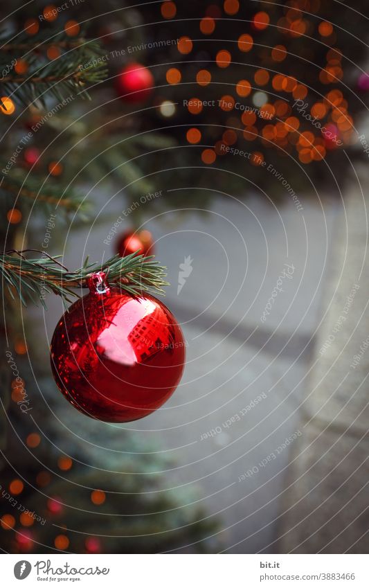 Rote Christbaumkugel, hängt am Weihnachtsbaum, auf Weihnachtsmarkt, vor glänzendem Bokeh. Weihnachten & Advent Weihnachtsdekoration Weihnachtsbeleuchtung