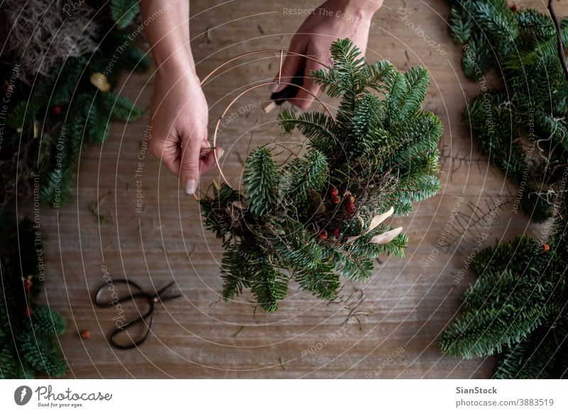 Frau macht Weihnachtskranz aus Fichtenholz, Schritt für Schritt. Konzept der Arbeit des Floristen vor den Weihnachtsfeiertagen. flache Verlegung Niederlassungen