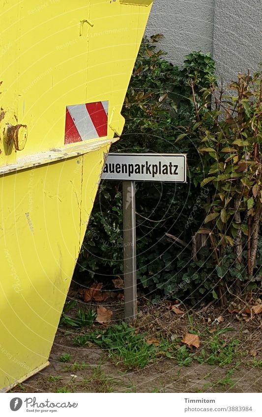 Gelber Container steht auf einem dafür nicht vorgesehenen Parkplatz gelb Frauenparkplatz Schild Zweckentfremdung Boden Gras Gestrüpp Schilder & Markierungen