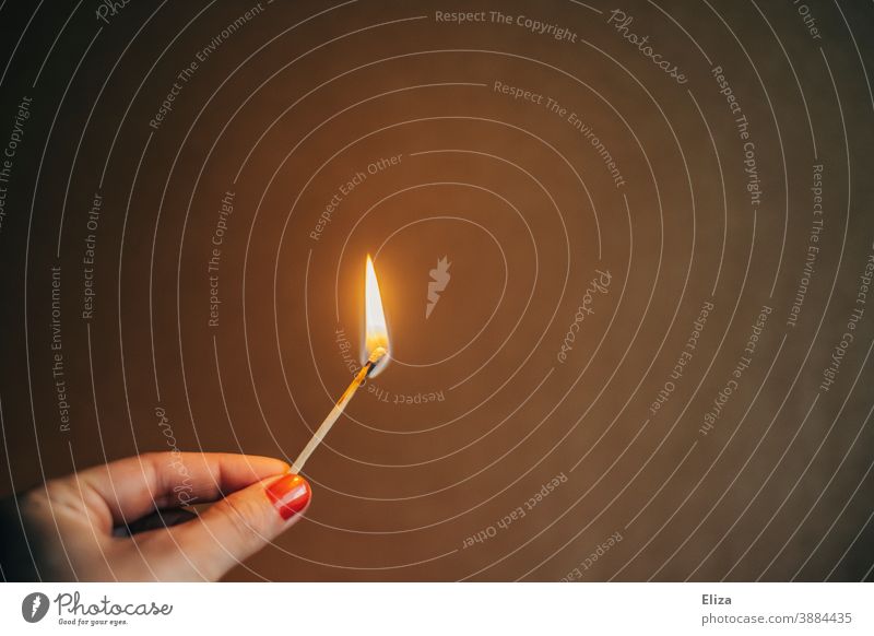 Weibliche Hand hält ein brennendes Streichholz anzünden Flamme entzünden Feuer weiblich Nagellack heiß Licht zündeln Wärme Zündholz