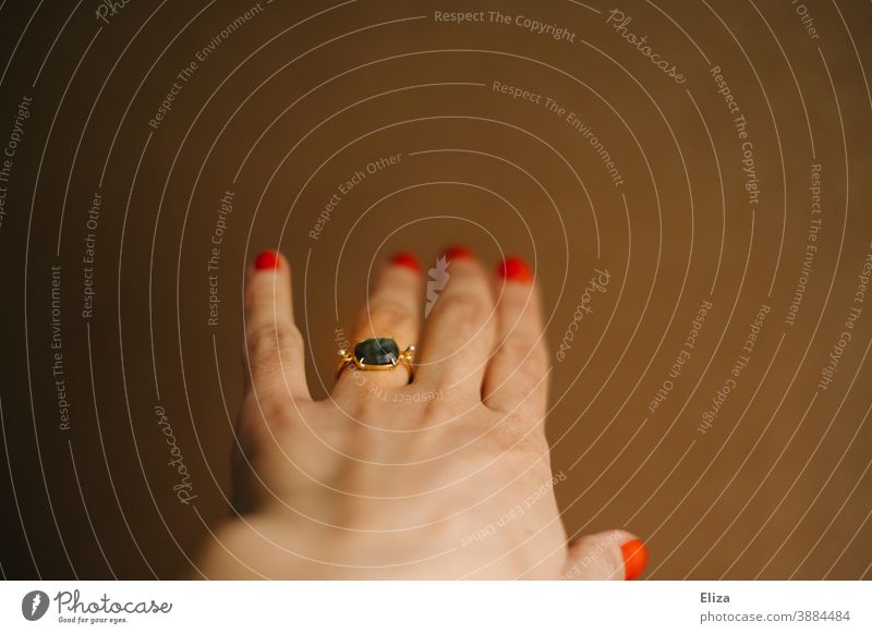Linke Hand einer Frau mit einem Ring am Ringfinger Verlobungsring Schmuck verlobt weiblich lackierte Nägel Finger feminin