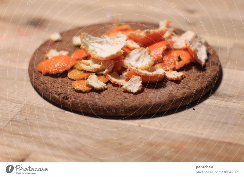 Mandarinenschalen liegen auf einem Untersetzer aus Kork auf einem Holztisch. Winter. Vitamin c mandarinenschalen geschält obst frucht gesund ernährung kork