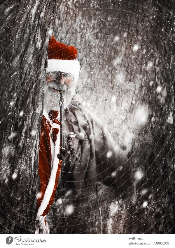 Der Weihnachtsmann schaut hinter verschneiten Bäumen hervor Nikolaus Pfeife Brille Sack Bart Vollbart grauhaarig Mantel Kostüm Tradition Weihnachtsmannmütze