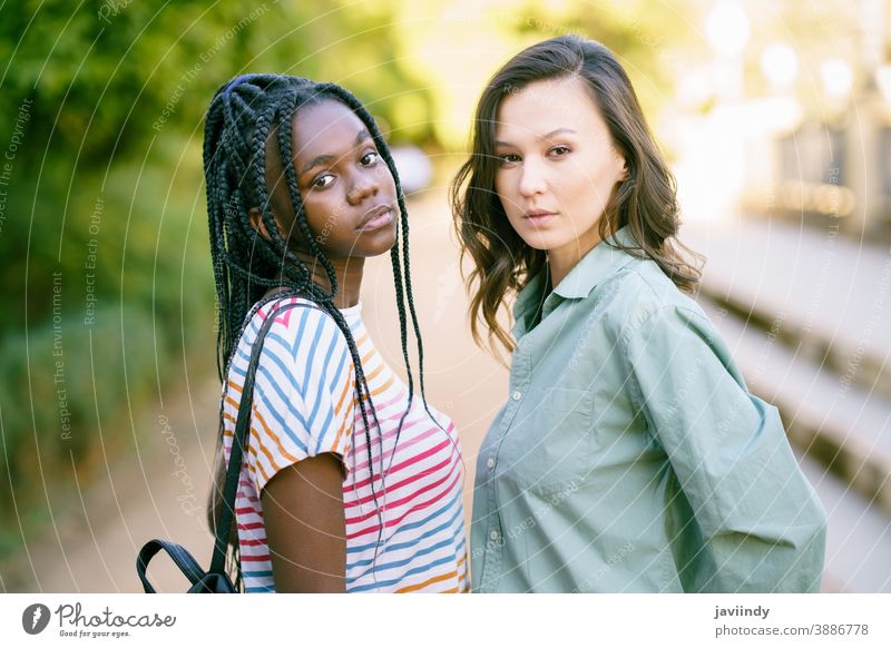 Zwei junge Freunde schauen auf der Straße gemeinsam in die Kamera. Multiethnische Frauen. multiethnisch schwarz Afro-Look Mädchen Schüler zwei Spaß Menschen