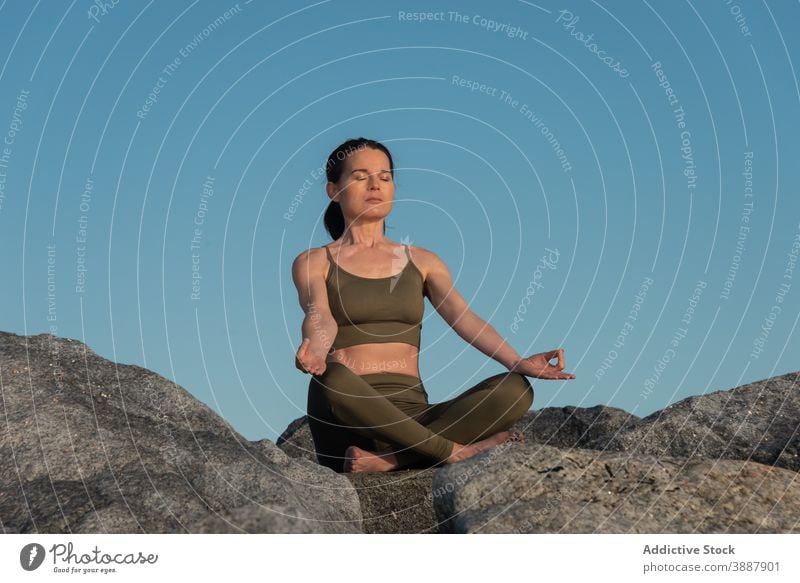 Entspannte Frau meditiert in der Natur meditieren Yoga Lotus-Pose Mudra sich[Akk] entspannen Stein Felsen Achtsamkeit Zen Asana padmasana üben Wellness Harmonie