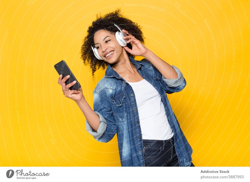 Glückliche schwarze Frau, die mit Kopfhörern Musik hört heiter zuhören Drahtlos Smartphone Spaß haben Hipster genießen jung Afroamerikaner ethnisch Optimist