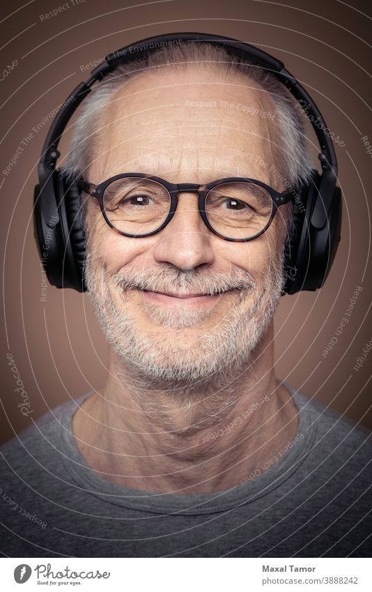Porträt eines erwachsenen Mannes mit Bart, der einen Stereokopfhörer und eine Brille trägt. Erwachsener attraktiv Audio Vollbart Junge lässig Kaukasier heiter