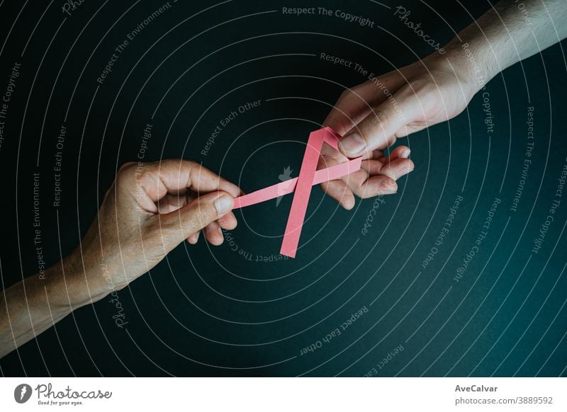 Eine alte Hand gibt einer jungen Hand eine rosa Schleife Erkenntnis Symbol Bändchen Brustkrebs blanko Almosen Kur krank nachschleppend Textfreiraum Überleben