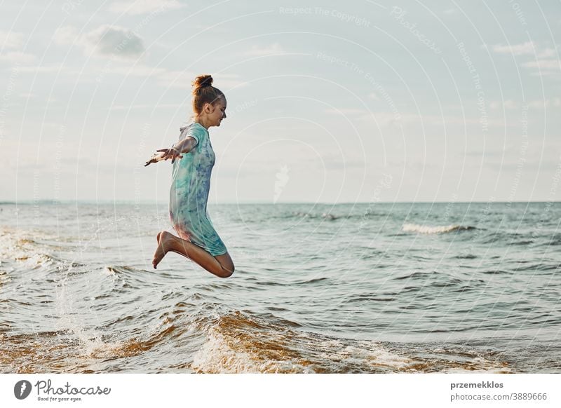 Mädchen, das es genießt, im Sommerurlaub über Wellen zu springen und seine Freizeit am Strand über dem Meer zu verbringen aufgeregt frei genießen positiv