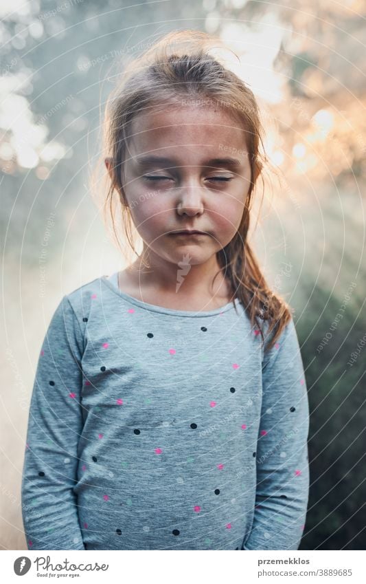 Trauriges kleines Mädchen mit geschlossenen Augen steht im Rauch zurück zum Sonnenlicht Kind Porträt zugeklappt Sonnenschein Gedanke Traurigkeit traurig