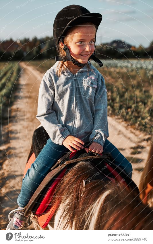 Kleines lächelndes Mädchen lernt Reiten Kind Mitfahrgelegenheit Pferd üben Schule niedlich Land hübsch ländlich Ranch Lektion Reiter Fröhlichkeit lernen