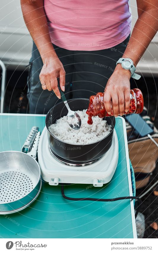 Frau kocht während der Sommerferien auf dem Campingplatz auf einem Elektroherd Reisgericht Mittagessen Outdoor-Küche heiß Topf Speise Koch Mahlzeit im Freien
