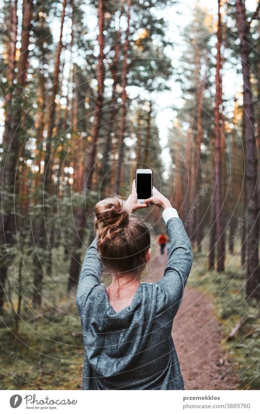 Junge Frau fotografiert mit einem Smartphone während eines Waldspaziergangs in den Sommerferien aktiv Aktivität Ausflugsziel genießen Erkundung Wanderung