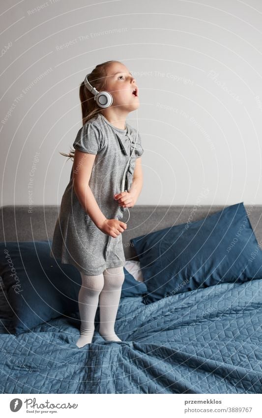 Kleines Mädchen singt tanzend und imitiert sich selbst als echte Sängerin Kind springend Spielen Gesang hören spielen singen Spaß Glück heimwärts Bett Kindheit