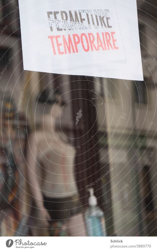 Covid-19 Pandemie Schaufenster eines zeitweise geschlossenen Geschäfts mit Hinweisschild in Französisch Schaufensterpuppe und Flasche mit Handdesinfektionsmittel