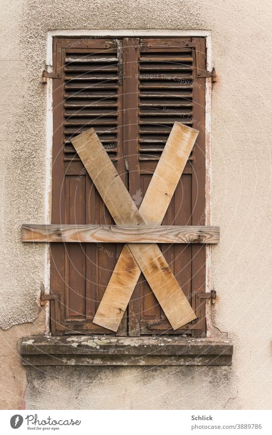 Total zu geschlossener alter Holzklappladen mit Brettern kreuz und quer vernagelt X marode verlassen unbewohnt Fassade Fenster Gebäude Haus Wand Menschenleer