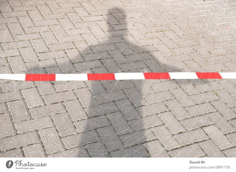 abgesperrt - Schatten eines Mannes hinterm Absperrband silouette verbot Person flatterband Absperrung isolation