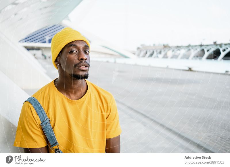 Schwarzer Mann steht auf der Straße und schaut in die Kamera trendy männlich ethnisch schwarz Afroamerikaner gelb Outfit Stil modern hell Vorschein