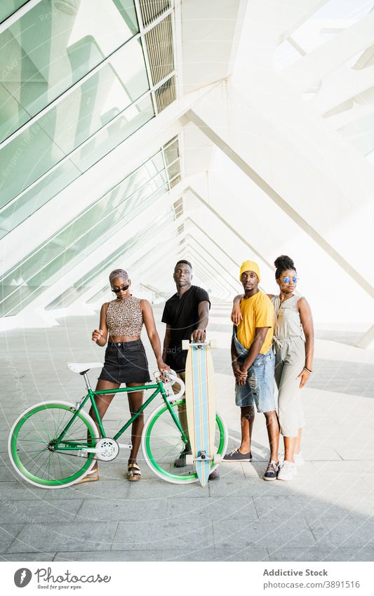 Gesellschaft von fröhlichen Freunden mit Fahrrad und Longboard in der Stadt Unternehmen Hipster Einheit cool Stil Generation Zusammensein ethnisch schwarz