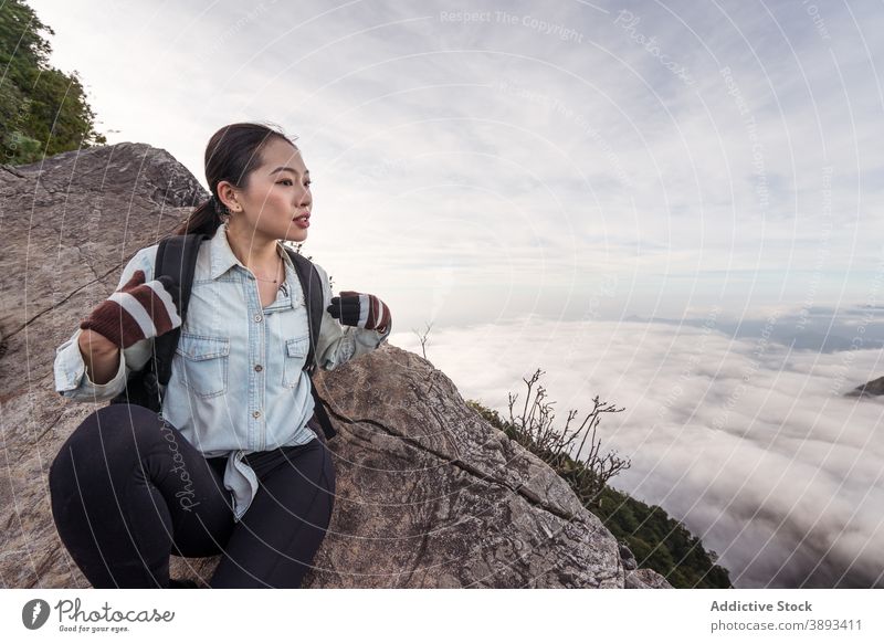 Asiatische Frau sitzt auf einem Felsen in den Bergen Berge u. Gebirge Reisender Cloud Hochland bewundern atemberaubend Wanderer Entdecker genießen asiatisch