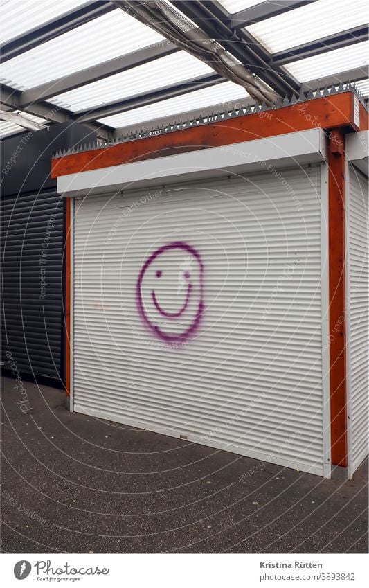 smiley auf geschlossenem rolladen eines marktstandes verkaufsstand gesicht lächeln positiv fröhlich freudig streetart street art graffiti urban art feierabend