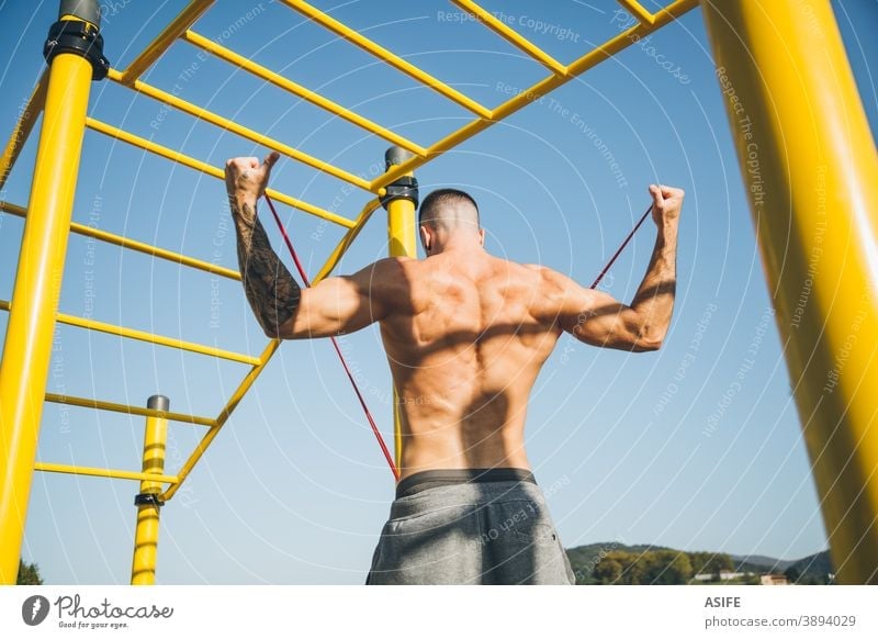 Junger Mann dehnt ein Widerstandsgummiband vor dem Training der Gymnastik calisthenics Sport Aufwärmen strecken Gummiband Widerstandsband Athlet Muskeln Stärke