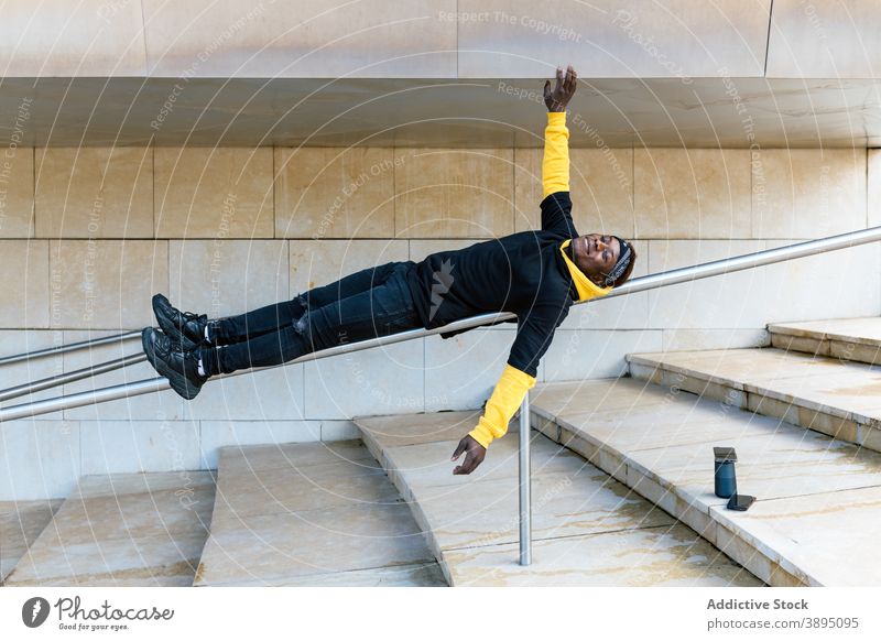 Junger schwarzer Mann auf Geländer liegend Hipster Spaß haben Reling Schritt Lügen heiter Treppe trendy Stil Typ jung Afroamerikaner ethnisch männlich modern