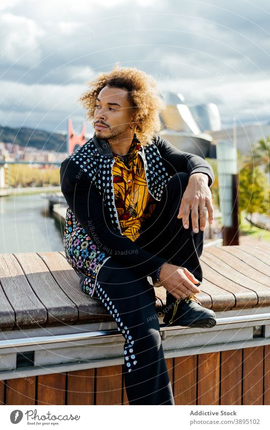 Selbstbewusst trendy Hipster Mann ruht auf der Straße Stil informell Mode krause Haare Vollbart jung modern farbenfroh Outfit Typ Afroamerikaner schwarz