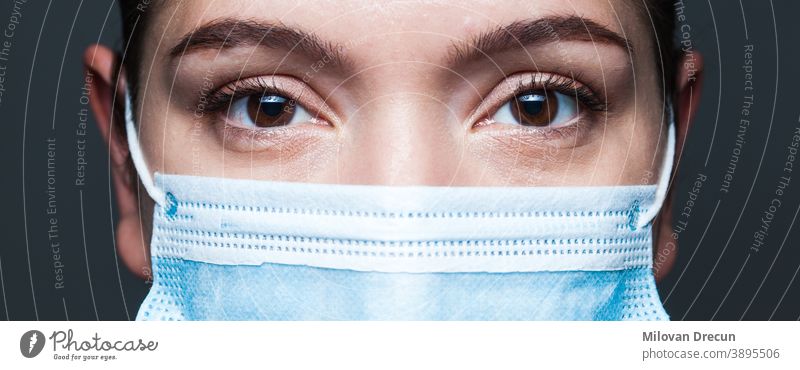 Junge kaukasische Frau mit blauer chirurgischer Gesichtsmaske Nahaufnahme-Breitbildportrait Coronavirus covid-19 Porträt Auge Mundschutz Arzt Transparente