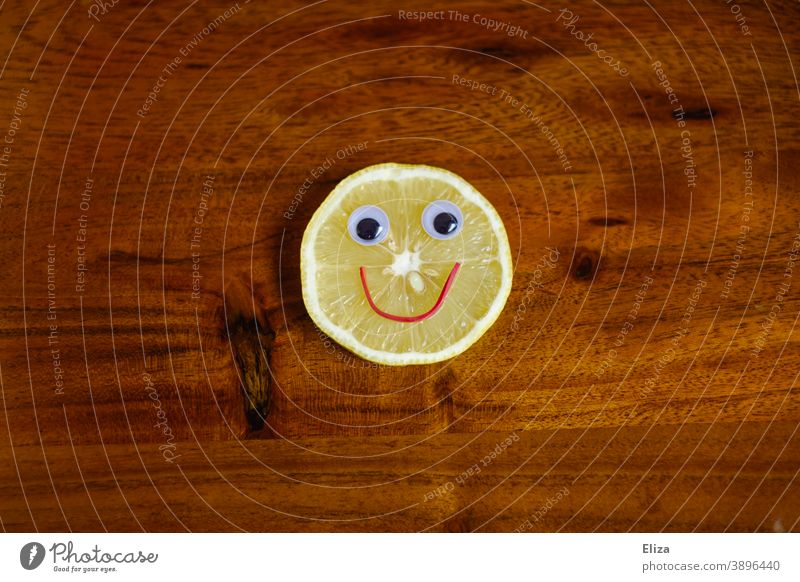 Sauer macht lustig - Zitronenscheibe mit lachendem Gesicht auf Holz sauer fröhlich Vitamine gesund Vitamin C gelb Lebensmittel vitaminreich gute Laune rund