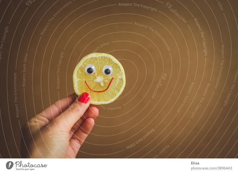 Sauer macht lustig  - Eine Hand hält eine Zitronenscheibe mit lachendem Gesicht sauer fröhlich Vitamine gesund Vitamin C gelb Lebensmittel vitaminreich