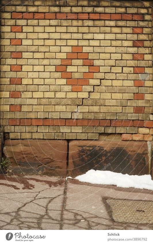 Letzter Schnee vor einer Backsteinmauer mit treppenförmigem Riss Mauer Backsteine Schafe Asphalt hintergrund verrotten beige Risse Buntsandstein Sandsteinblöcke