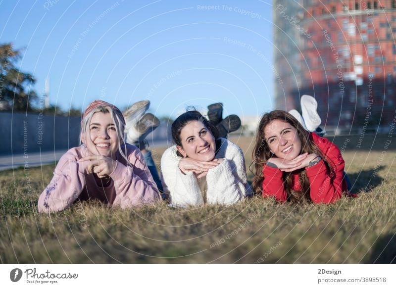 Drei schöne junge Frauen liegen auf dem Rasen, ruhen sich aus und träumen im Park auf dem grünen Gras. Glück Lügen drei Lächeln Freundschaft Boden Freunde
