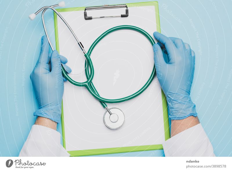 die Hände einer Ärztin in blauen Latexhandschuhen, die ein Metallstethoskop halten Papier Stethoskop Chirurg Werkzeug Behandlung Zwischenablage Frau Arbeiter